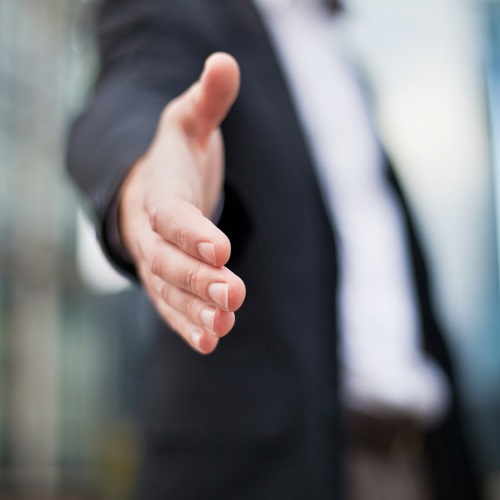 stock-photo-businessman-offering-for-handshake-on-office-buildings-background-med